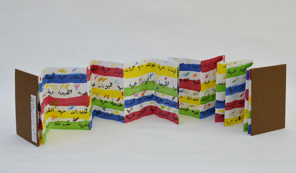 A photograph of an unfolded book with Arabic writing inside of it, offset by colored bands