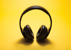 A pair of headphone photographed against a yellow background