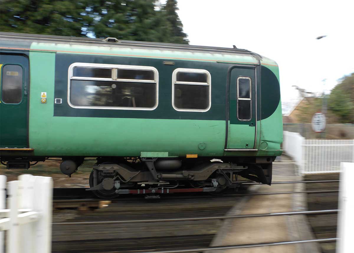 Green train passing platform outside