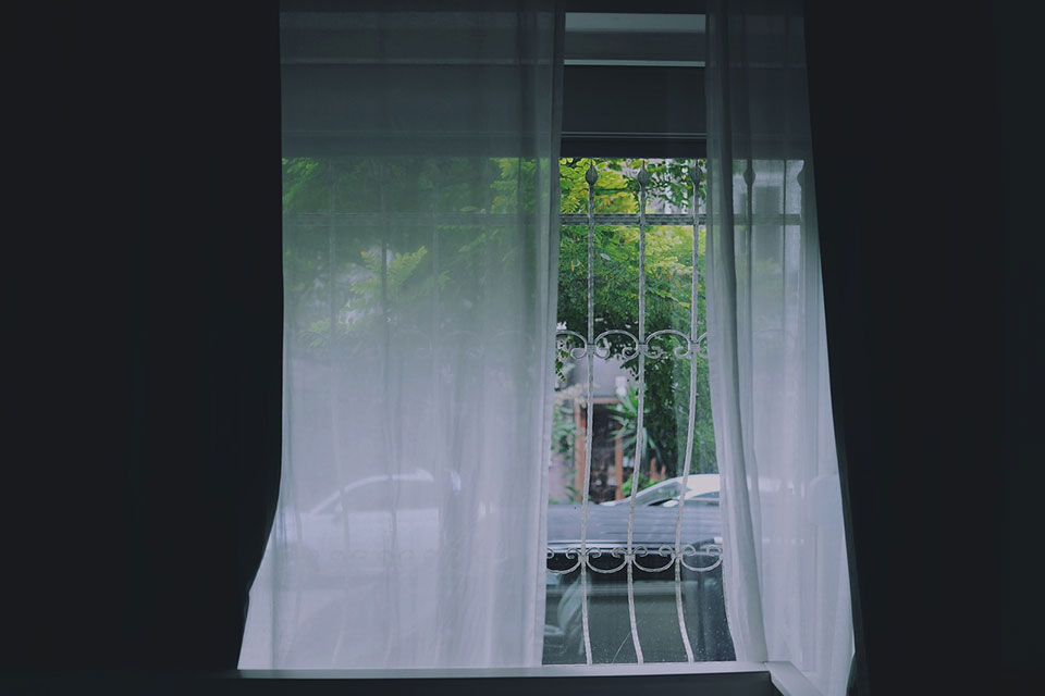 An open window with loose white curtains
