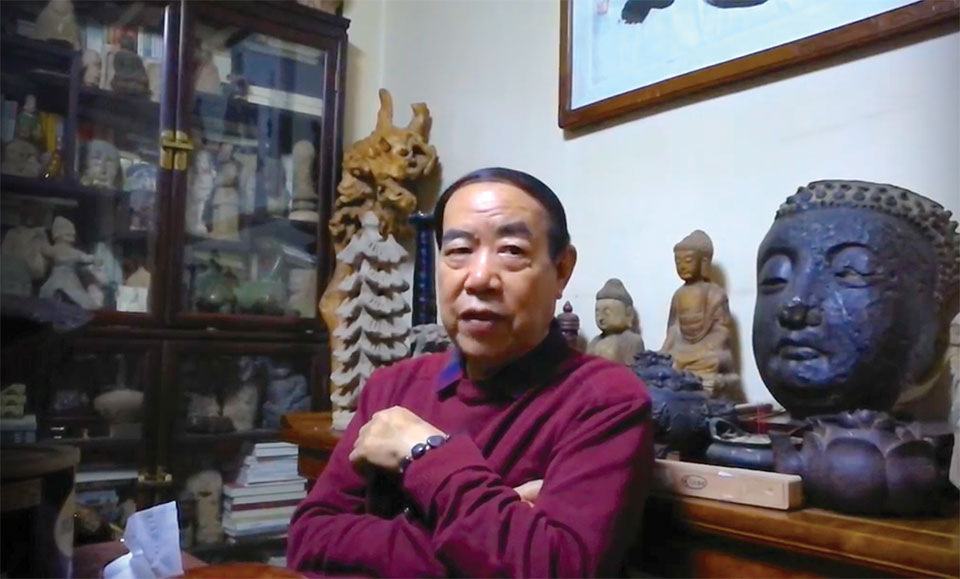 Author Jing Pingwa sits, arms crossed casually, in front of a number of religious icons