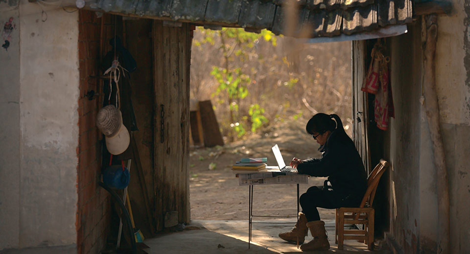 A photograph of Yu Xiuhua writing on a laptop