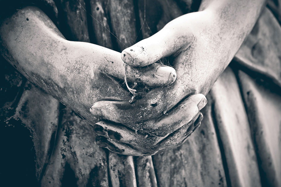 A close-up of the weather worn hands of a angel statue