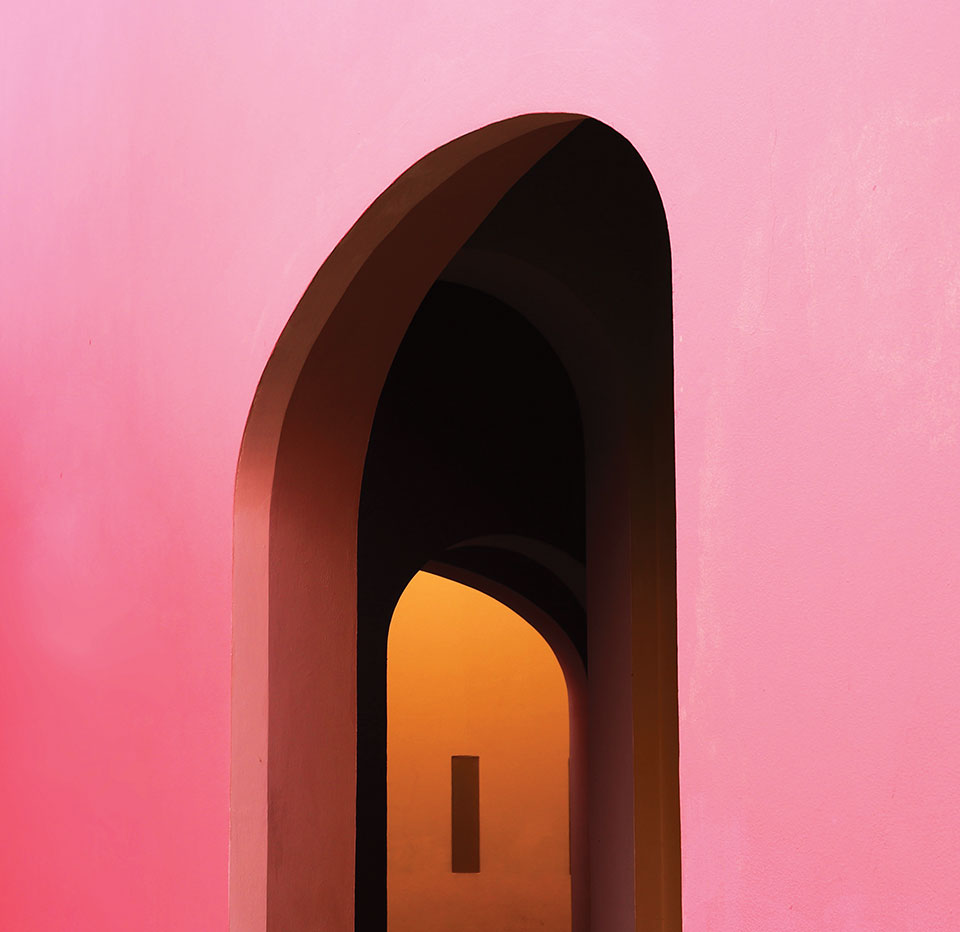 A photograph of a door in a pink wall through which we can see another doorway that opens into an orange room