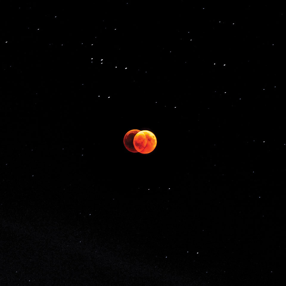A double-exposed image of the moon, tinged red