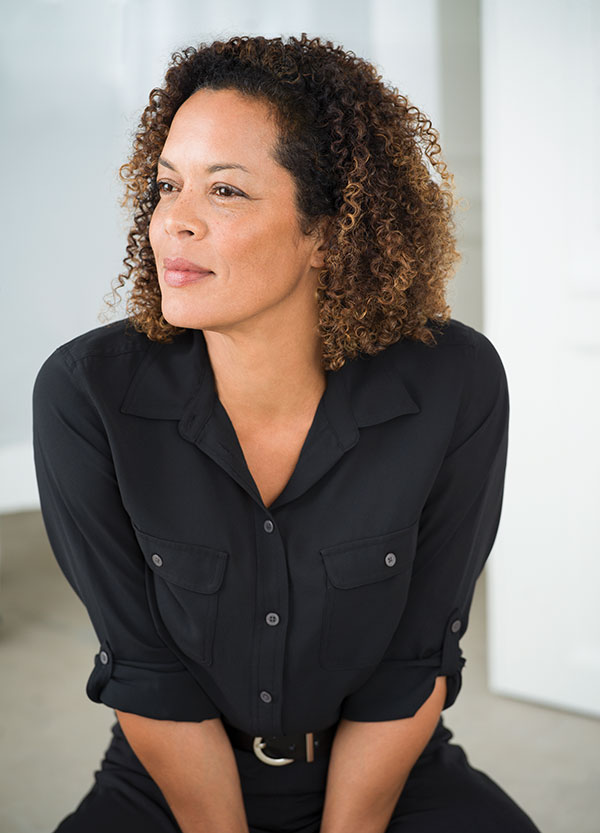 Aminatta Forna sits looking off panel, clad in black
