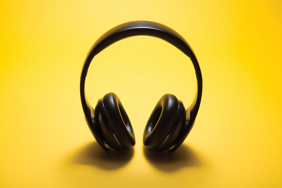 A pair of headphone photographed against a yellow background