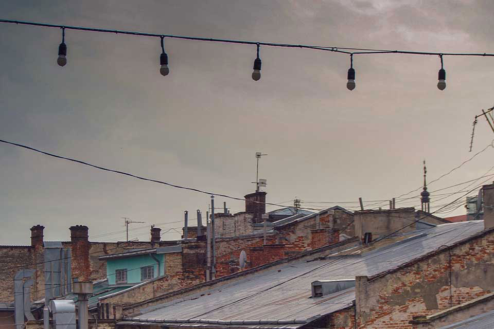 A photograph of a string of unlit lamps strung above an urban landscape