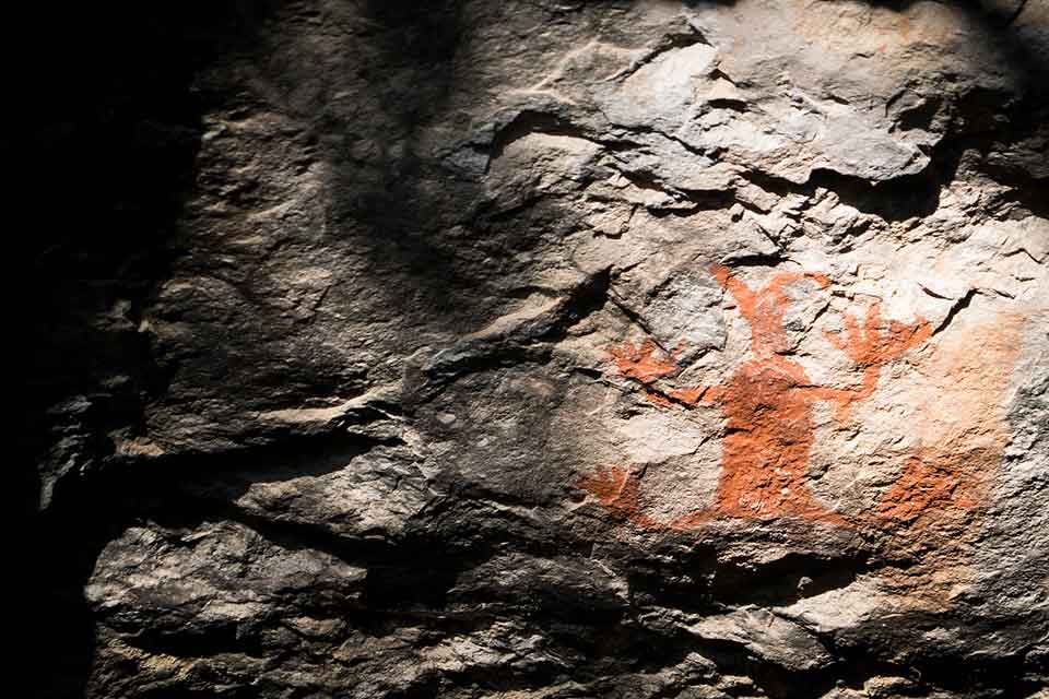 A photograph of a crude ochre painting on a cave wall