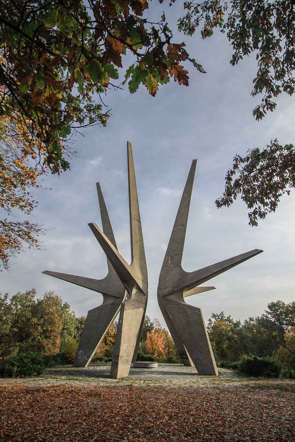 A photograph of an outdoor monument with three geometric figures rising up out of the ground