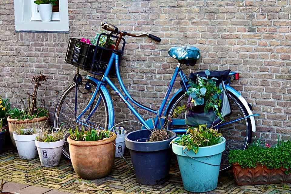 A photograph of a blue bicycle leaning up against a brick wall