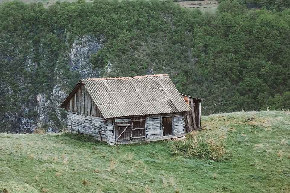 A photograph of an old house on a grassy hilltop