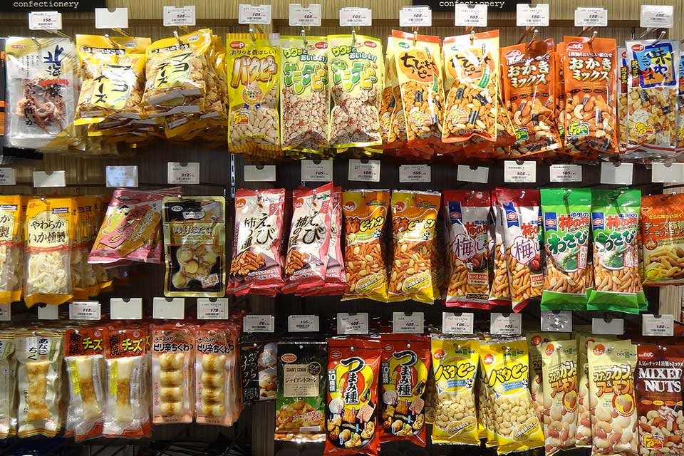 Packaged foods hang uniformly from wall pegs in a Japanese convenience store
