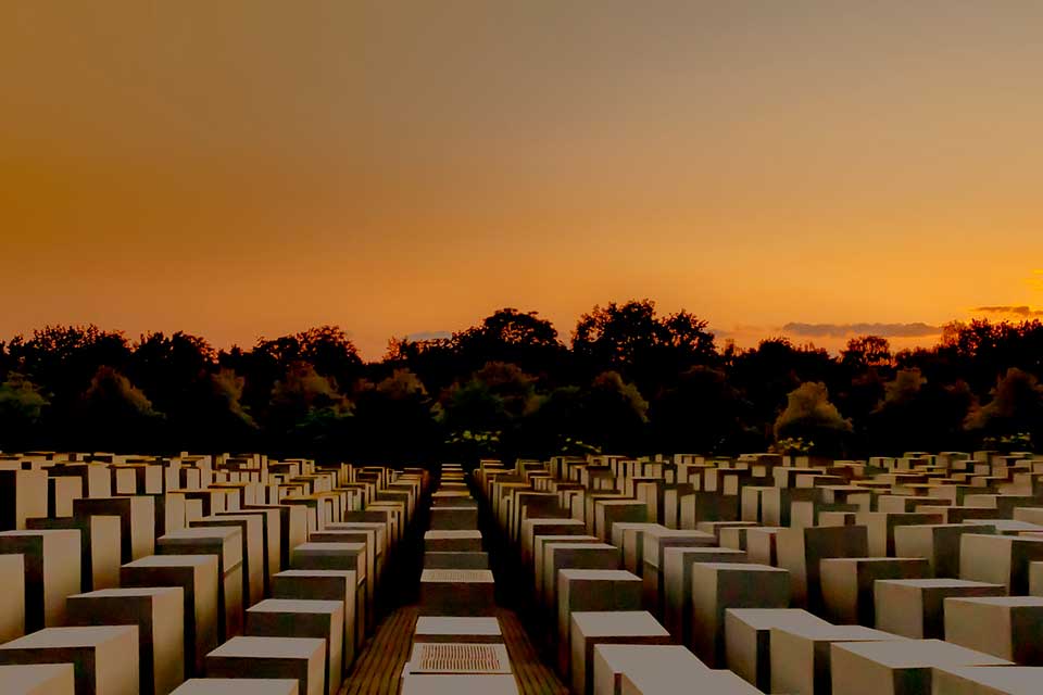 Numerous uniformly cube shaped objects serving as memorials in a field bathed in the colors of sunset