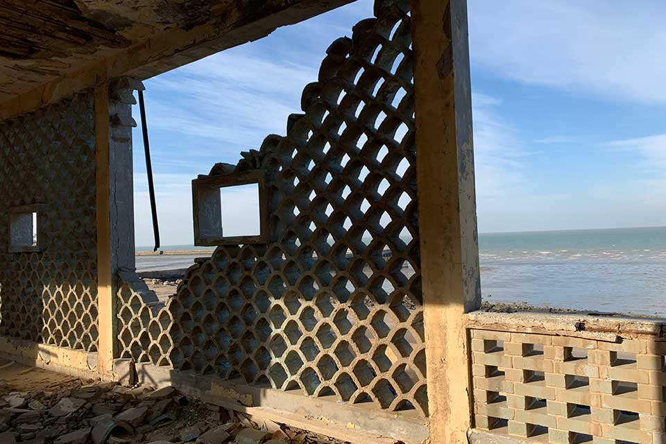 A photograph from inside a crumbling building that looks out toward the sea