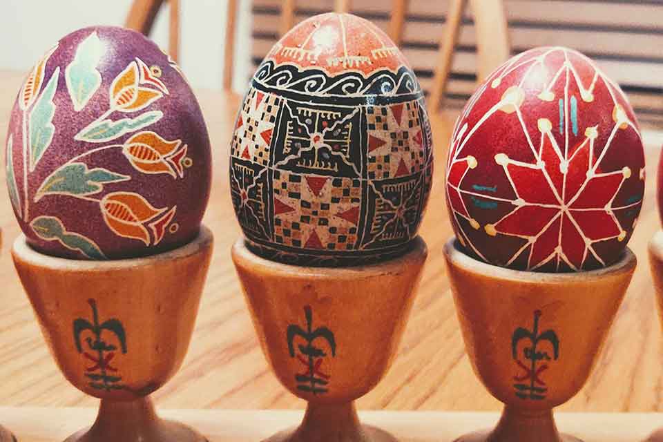 A photograph of three ornately lacquered eggs resting in wooden stands