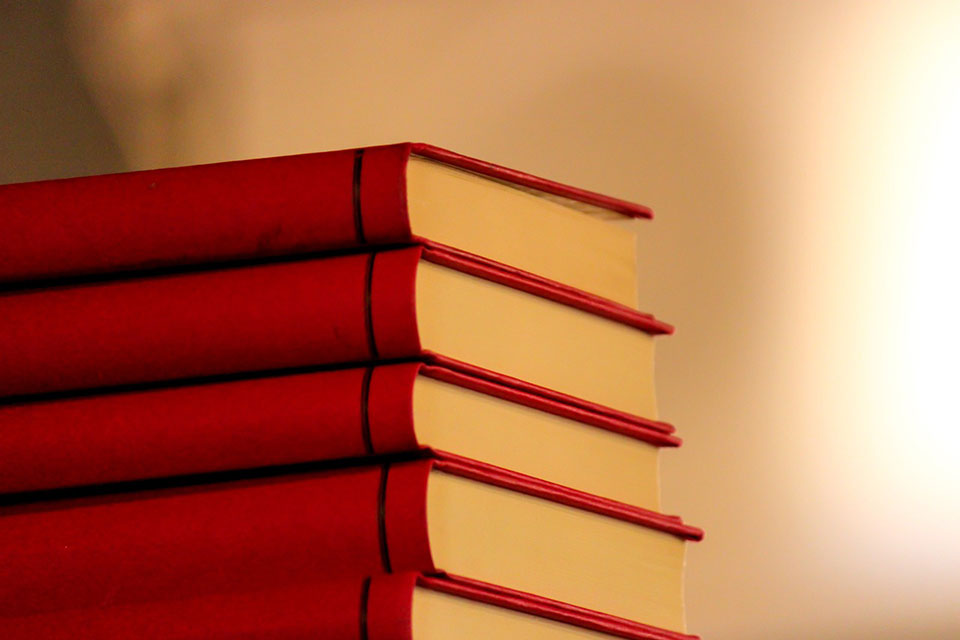 A stack of five red books with a warm glow around it