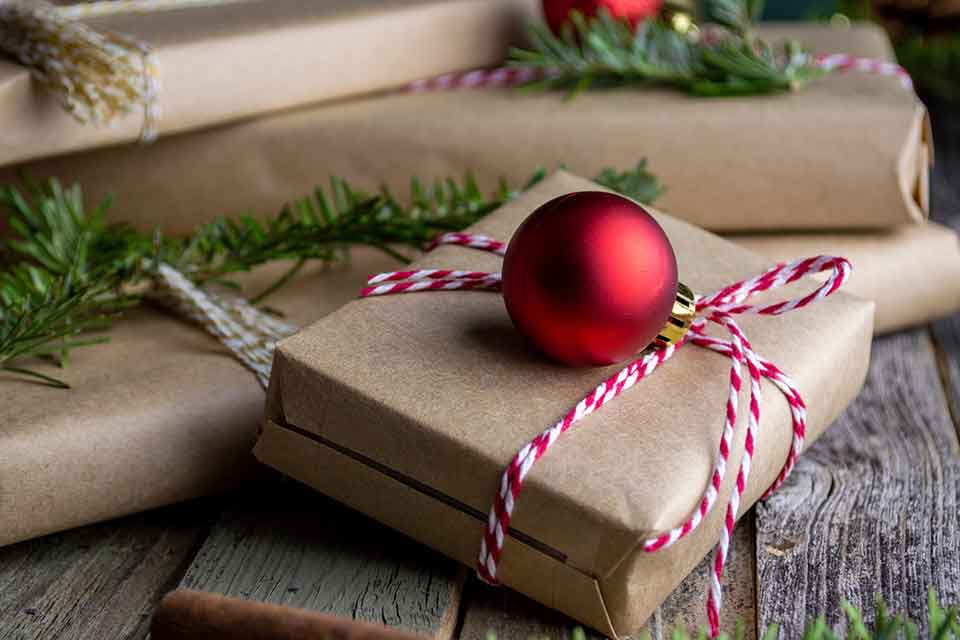 A photograph of books wrapped as gifts with a red ornament laying atop the one in the center