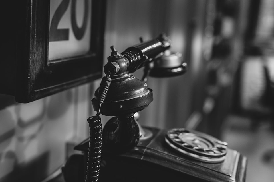 A black and white photo of a vintage phone in a study