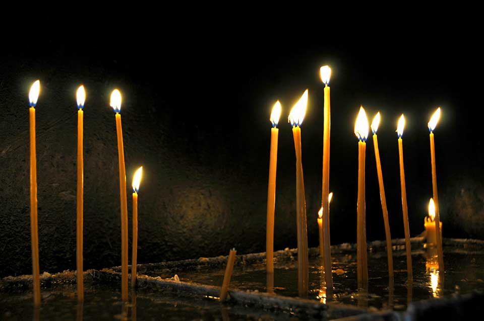 Thin, tapered, and lit candles arising from water