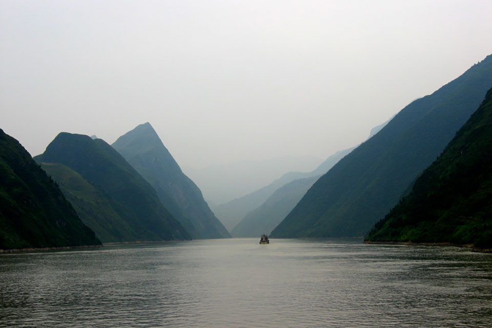 A photograph of a foggy river with a boat visible in the distance