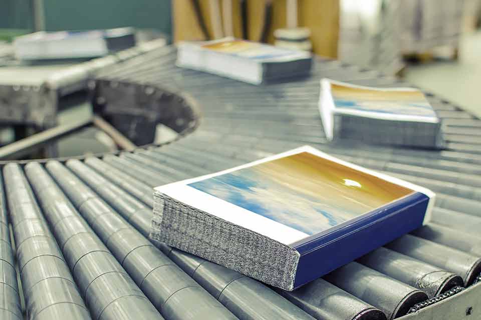 Books riding on a curved conveyor belt prior to binding