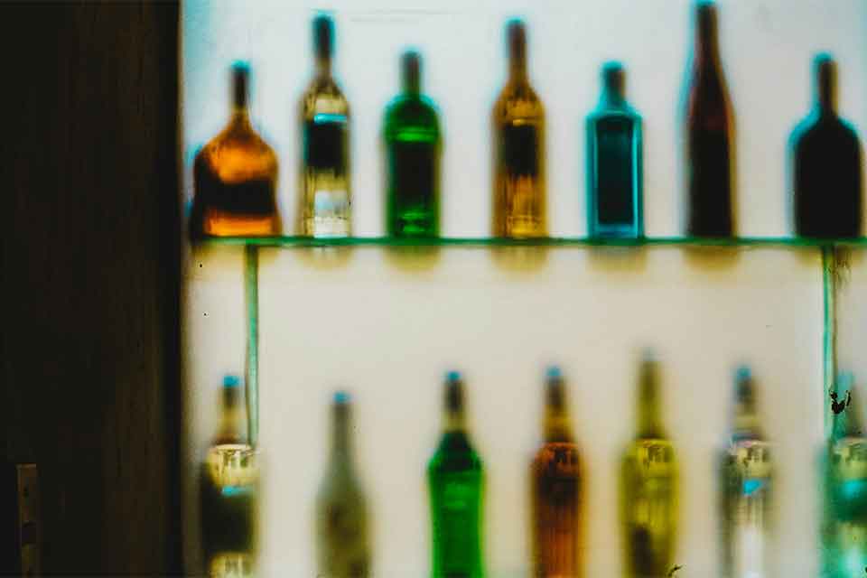 The back shelf of a bar, the colored bottles of spirits out of focus
