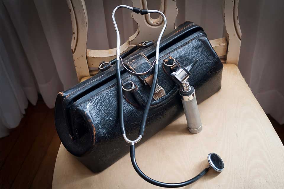 A medical bag with a stethoscope and an otolaryngioscope visible