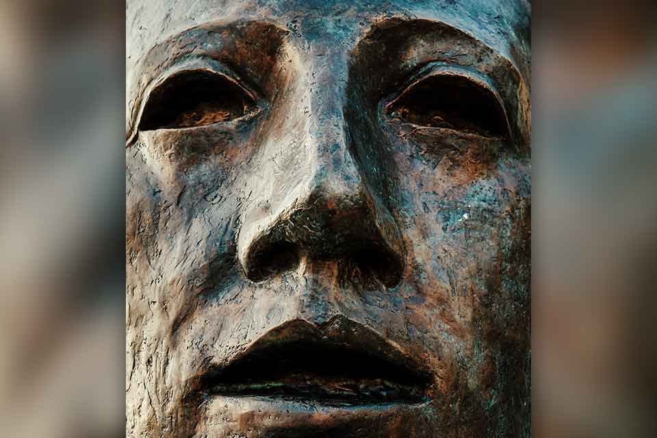 A close up of a human face in bronze