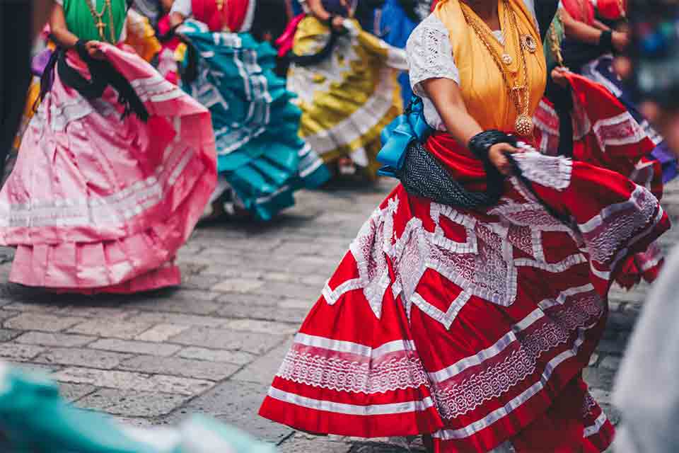 The lower torso of women in traditional Mexican dress dancing in tandem