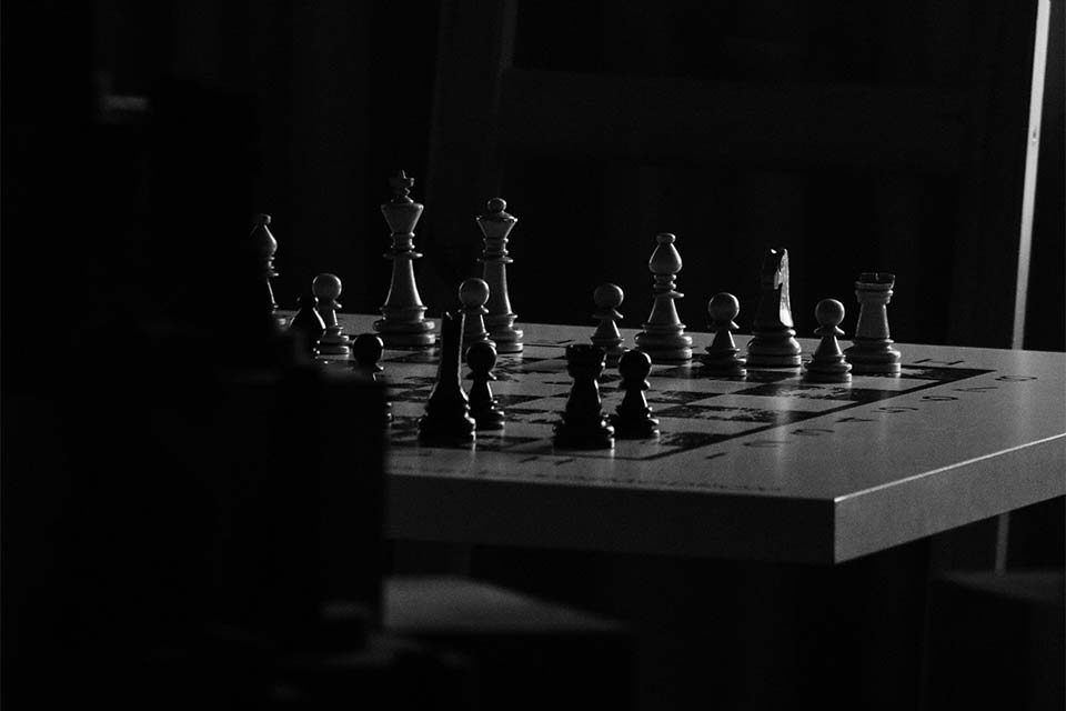 A chessboard in a room consumed by shadows