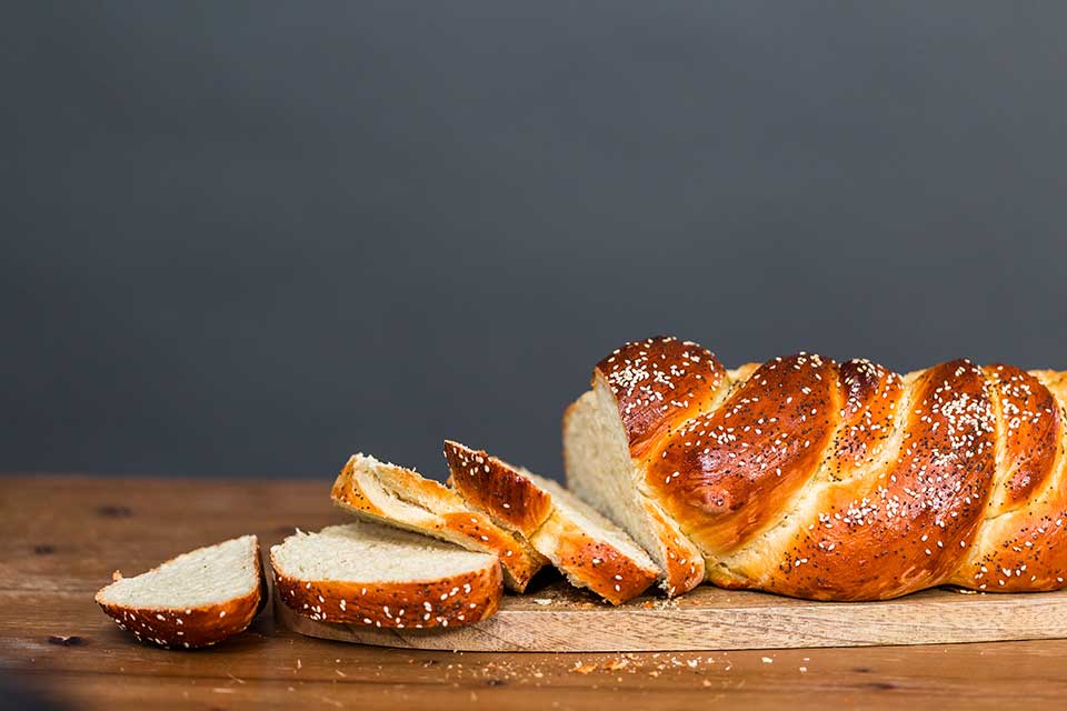 A loaf of baked bread with slices cut off from one end that spill on to the table