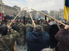 A photograph of a group of three people holding long wooden poles to their face in a crowd of protesters