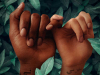 A digital illustration. Two dark skinned hands are bound by a interwoven pinky fingers. Both hands have words in Arabic written on the wrist.