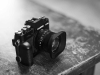 A black and white photo of a Fuji camera on a wooden table