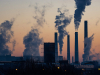 A photograph of an industrial park at dusk, smoke belching from tall stacks