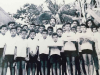 A black and white photograph of a woman standing behind a group of children