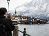 A person stands on the outskirts of an Alpine city taking a photo of it with his phone