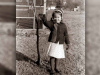 A black and white photograph of a young girl waving at the camera