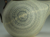 A detail of a photograph of a tea pot, focusing on a spiral on its belly