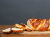 A loaf of baked bread with slices cut off from one end that spill on to the table