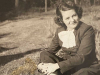 A sepia-toned photograph of a young woman sitting on a grass lawn.