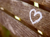 A photograph of a wooden bench with a heart drawn on it in chalk