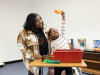 A woman stands beside a child as they look at a brightly colored toy in their hands