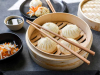 A photograph of steamed dumplings in a bamboo tray