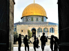 A photograph of children, bathed in shadow, gathered in an arch that faces the Dome of the Rock