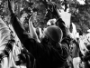 A black and white photo of a masked protestor with his hands up