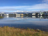 The city of Reykjavik framed in the foreground by a lake and in the background by cloud-capped mountains