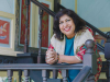 Dipika Mukherjee leans over a railing, smiling, as she looks at the camera