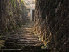 Steps, roughly cut from stone, leading steeply toward a door, partially obscured by the curvature of the rock